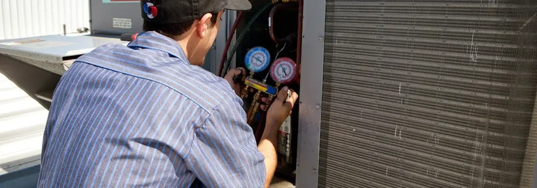 HVAC technician servicing a condenser unit in Clovis