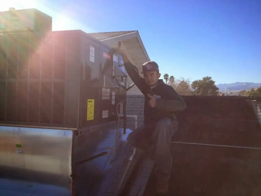 HVAC technician performing AC Tune-Up on a rooftop unit in Clovis